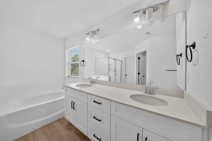 Double vanity featuring white cabinetry with black hardware, undermount sinks, and a light-toned countertop