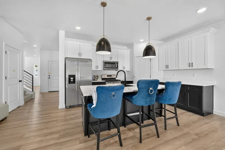 Modern kitchen featuring an island with counter seating, stainless steel appliances, white upper cabinetry, and dark lower cabinetry