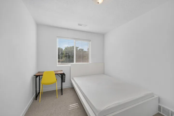 Carpeted room featuring a window with horizontal blinds, white walls, and a flush mount ceiling light fixture