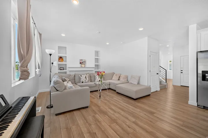 Open-concept living area with wood-finish flooring, recessed lighting, and white walls