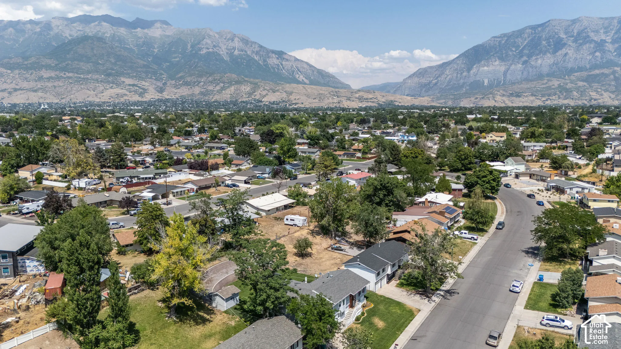 Expansive residential area featuring a curvilinear street, mature trees, and a mountain backdrop