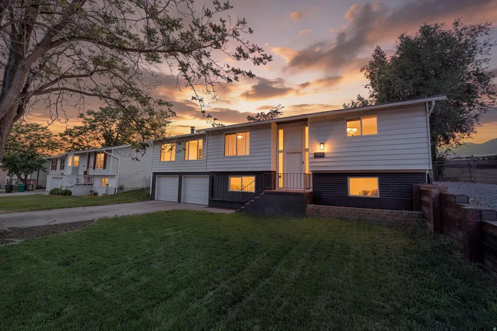 Split-level residence featuring light-colored siding and a dark-toned lower level