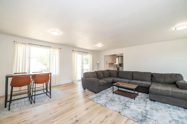 Spacious living area featuring light wood-finish flooring, white walls, and contemporary ceiling light fixtures