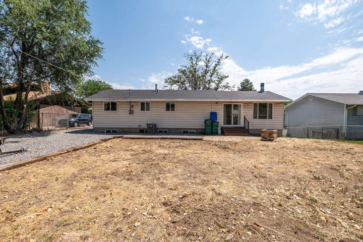 Expansive rear yard space featuring a gravel patio area and mature perimeter trees