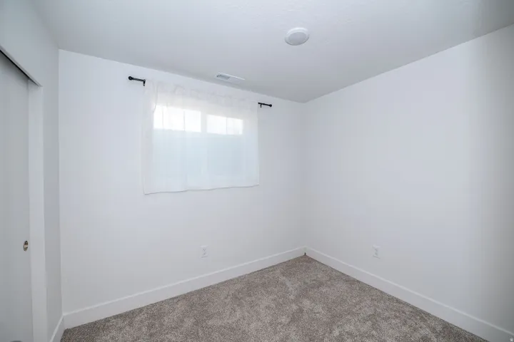 Bright interior space featuring white walls and neutral-toned carpeting