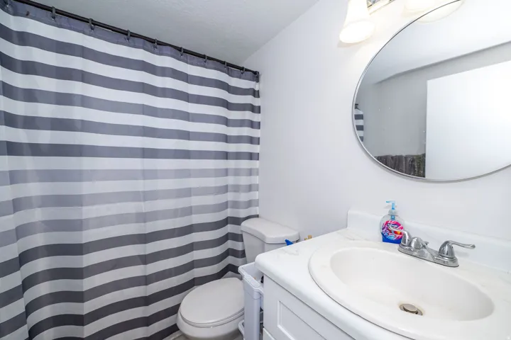 Bathroom featuring a white vanity with integrated sink, chrome faucet, and circular wall mirror