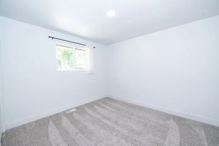 Neutral-toned carpeting paired with white walls, a single window, and a recessed ceiling light fixture