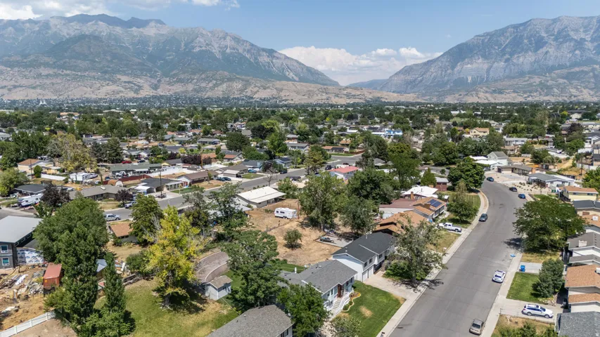 Expansive residential area featuring a curvilinear street, mature trees, and a mountain backdrop