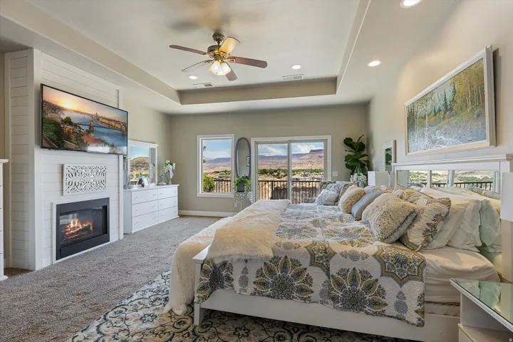 Spacious bedroom featuring a tray ceiling, recessed lighting, and a ceiling fan