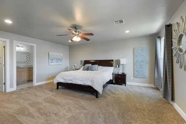 Spacious bedroom featuring plush carpeting, a ceiling fan with integrated lighting, and recessed overhead lighting