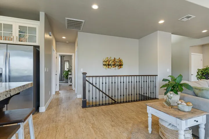 Open landing area featuring wood-finish flooring, recessed lighting, and a wrought iron staircase railing