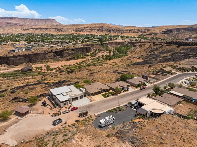 Expansive property featuring a modern residence with a flat roofline, a gravel driveway, and surrounding desert landscaping