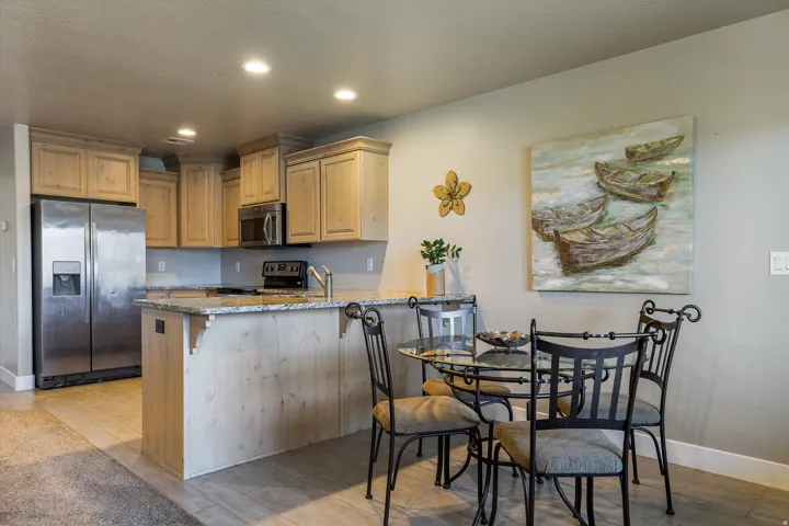 Kitchen featuring light wood cabinetry, stainless steel appliances, a granite-finish countertop, and recessed lighting