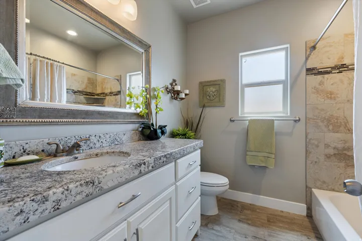 Bathroom vanity featuring a speckled countertop, integrated sink, and white cabinetry with brushed nickel hardware
