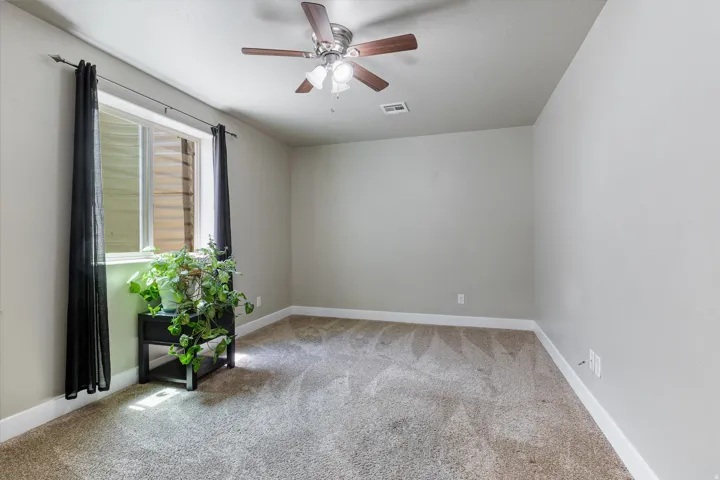 Carpeted room with a ceiling fan featuring wood-finish blades and integrated lighting