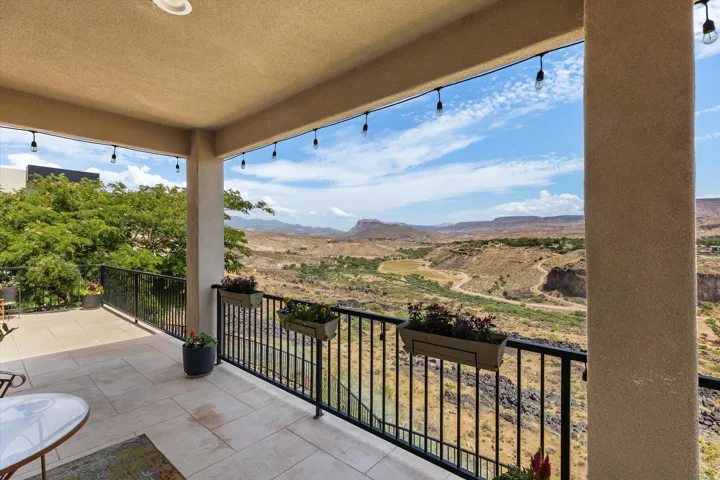 Covered outdoor patio featuring a neutral-toned tile floor, black metal railing, and recessed ceiling lighting