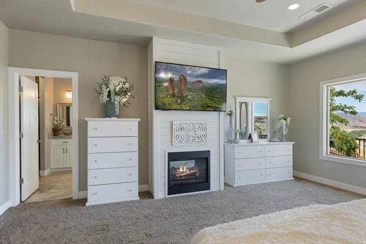 Carpeted room featuring a built-in fireplace with shiplap surround, tray ceiling, and a large window