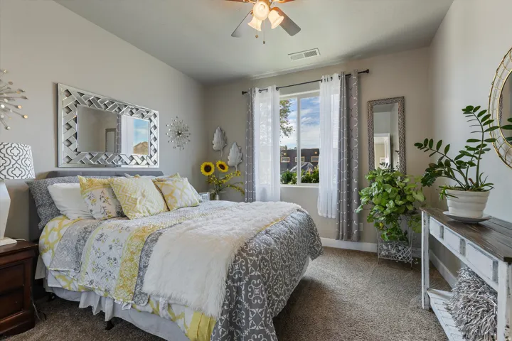 Carpeted bedroom with a window, ceiling fan, and light gray walls