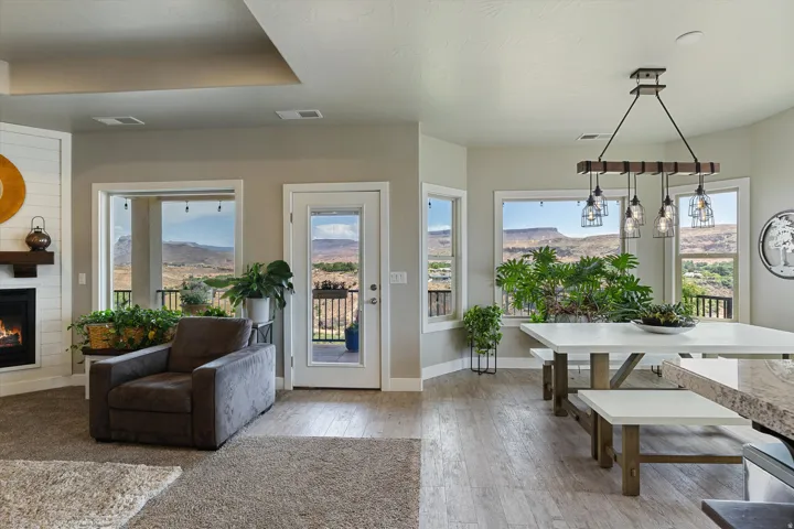 Open-concept living space featuring a fireplace with a shiplap surround, multiple windows, a glass-paneled exterior door, and wood-finish flooring