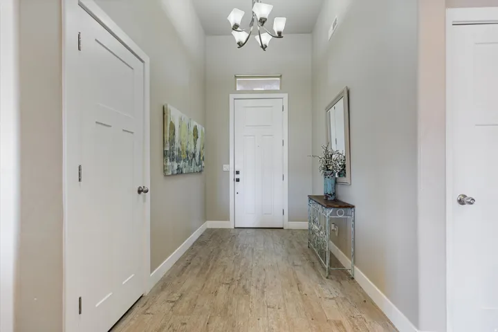 Entryway featuring wood-finish flooring, light neutral wall tones, white trim, and a high ceiling with a chandelier