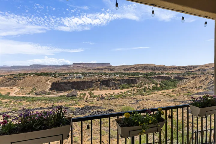 Expansive desert and mesa scenery from a balcony with a black metal railing and decorative string lights