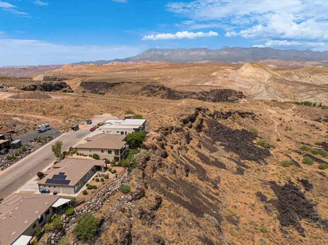 Homes situated along a desert landscape, featuring a paved road and mature mountain range backdrop