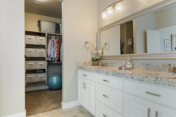 Dual vanity with a stone-finish countertop, white cabinetry, and brushed nickel hardware
