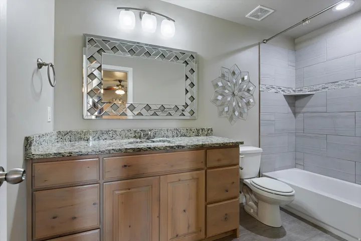 Bathroom featuring a single vanity with a granite countertop and wood-finish cabinetry