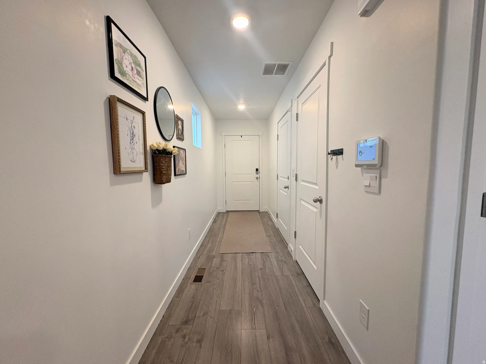 Hallway featuring wood-finish flooring, white walls, and recessed lighting