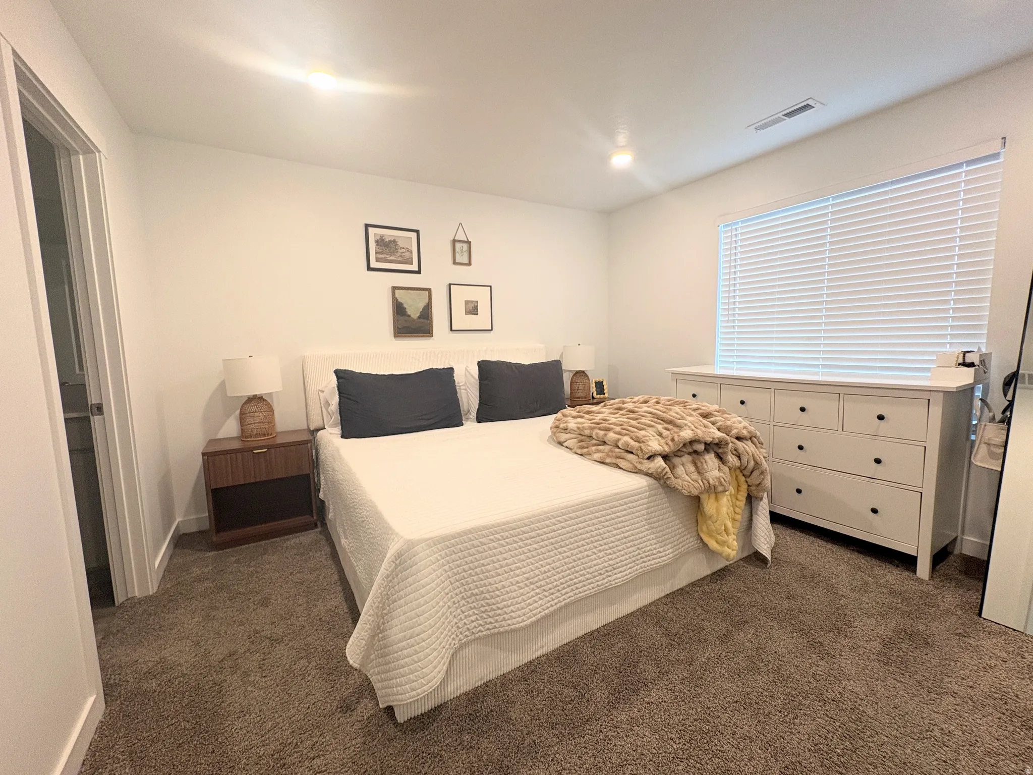 Interior room featuring white walls, textured carpeting, and a window with blinds