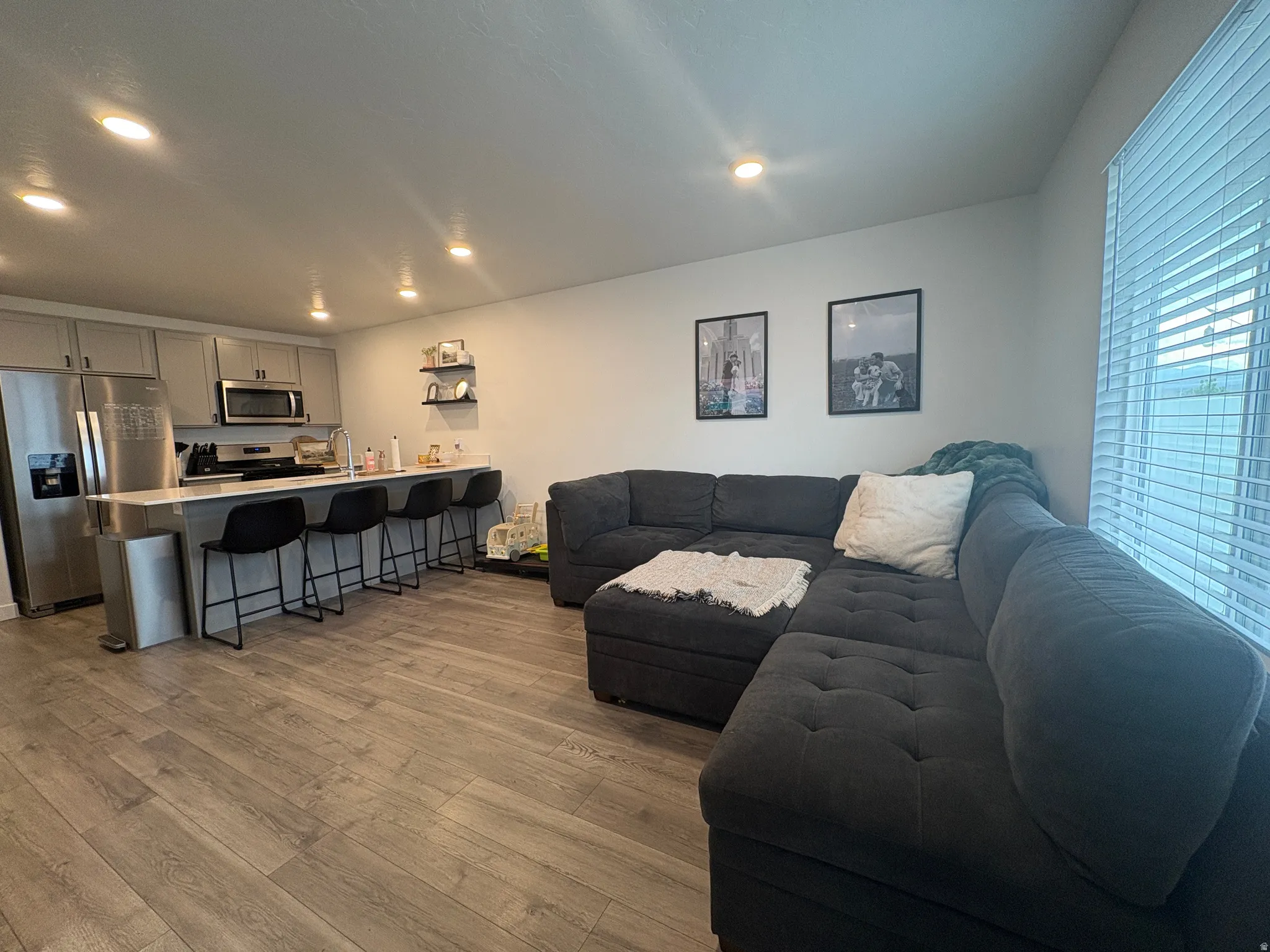 Open-concept living area featuring wood-finish flooring, recessed lighting, and a kitchen island with seating