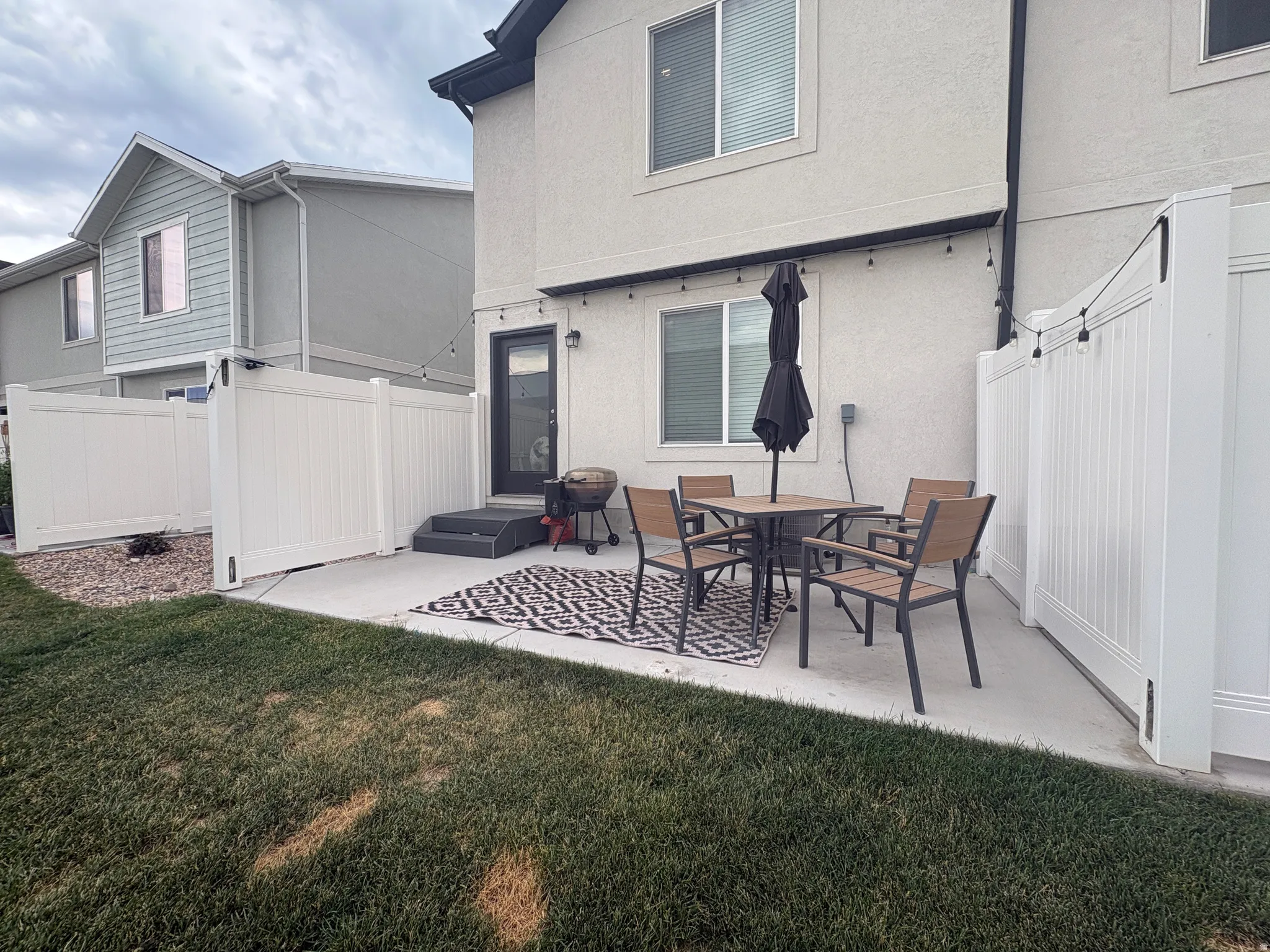 Private backyard patio with concrete slab and turf lawn