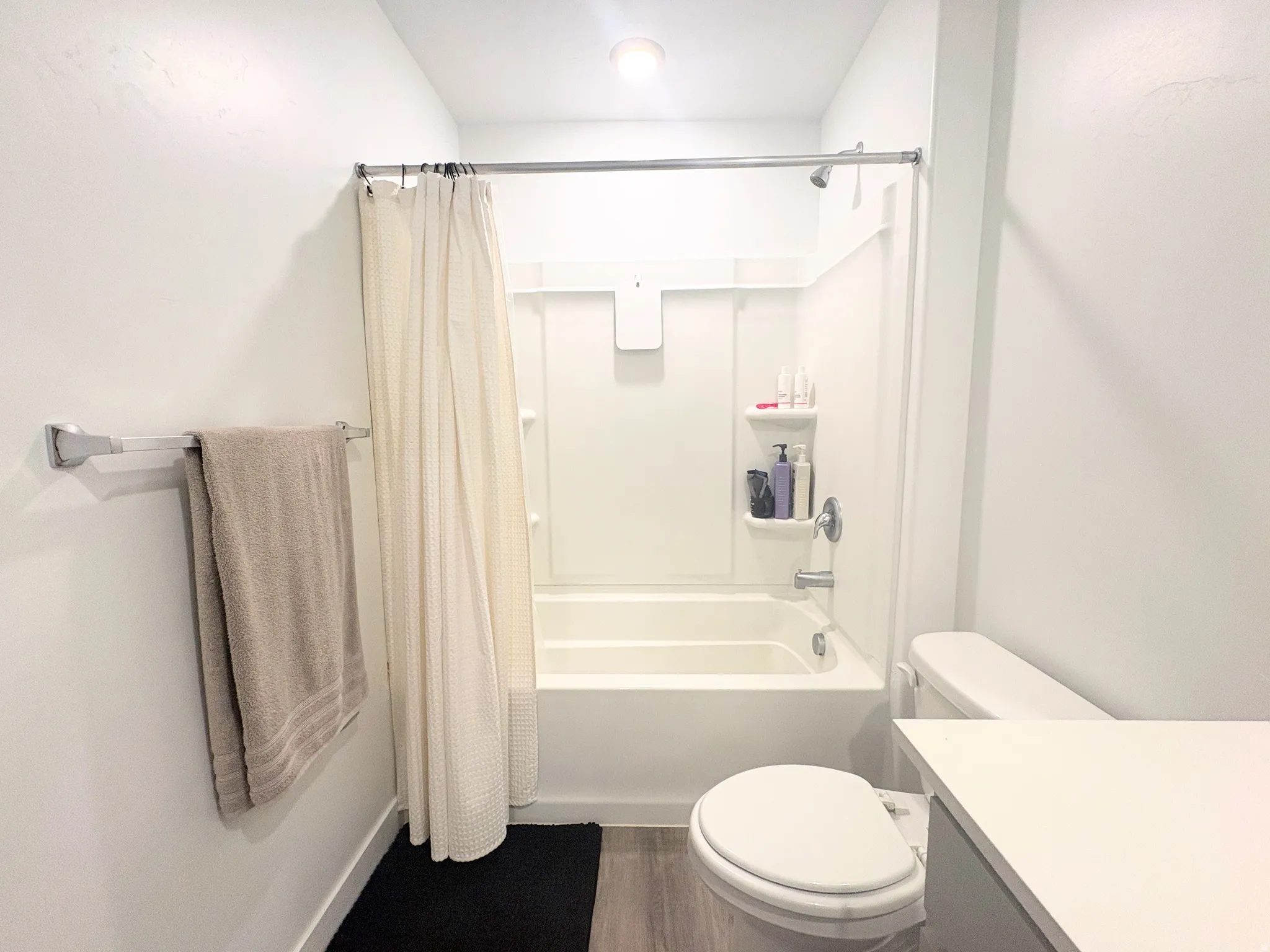 Bathroom featuring a white tub/shower combination, light wood-finish flooring, and a white toilet