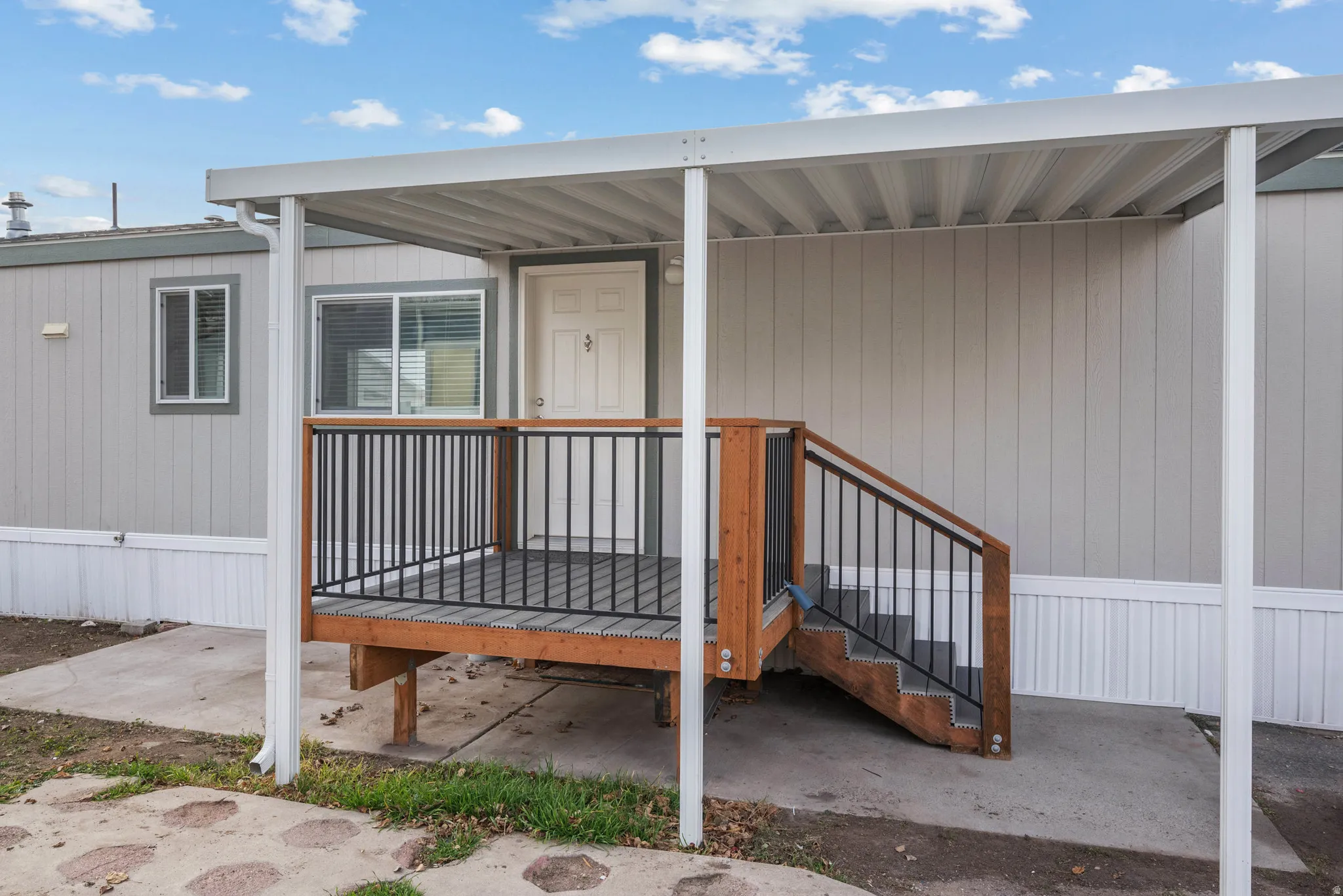 Covered entry porch featuring wood-finish decking and railing with dark balusters