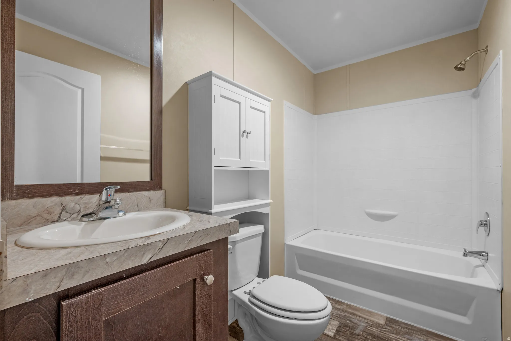 Bathroom featuring a wood-finish vanity with an integrated sink and a framed mirror