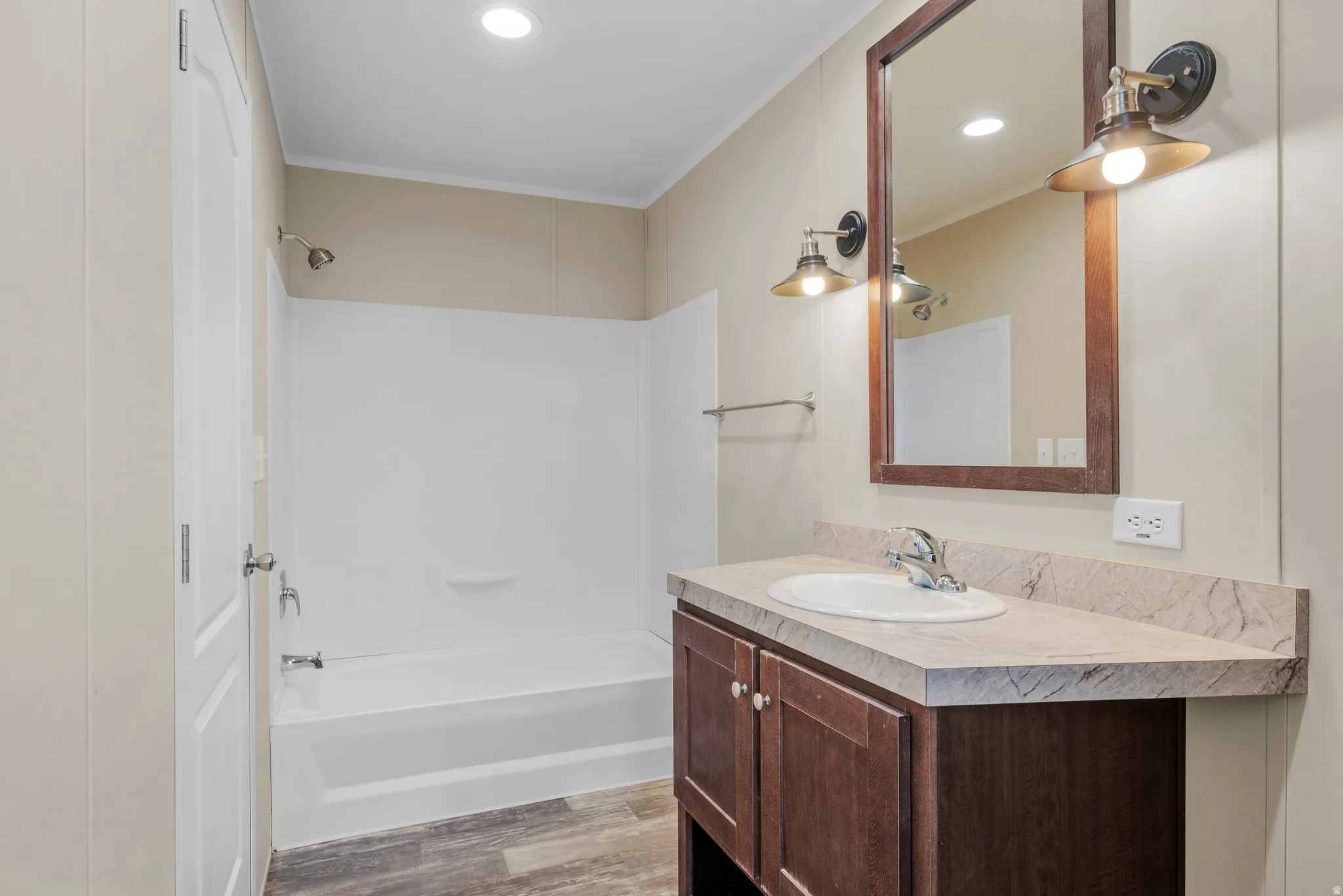 Bathroom featuring a wood-finish vanity with a built-in sink, a framed mirror, and two wall-mounted light fixtures