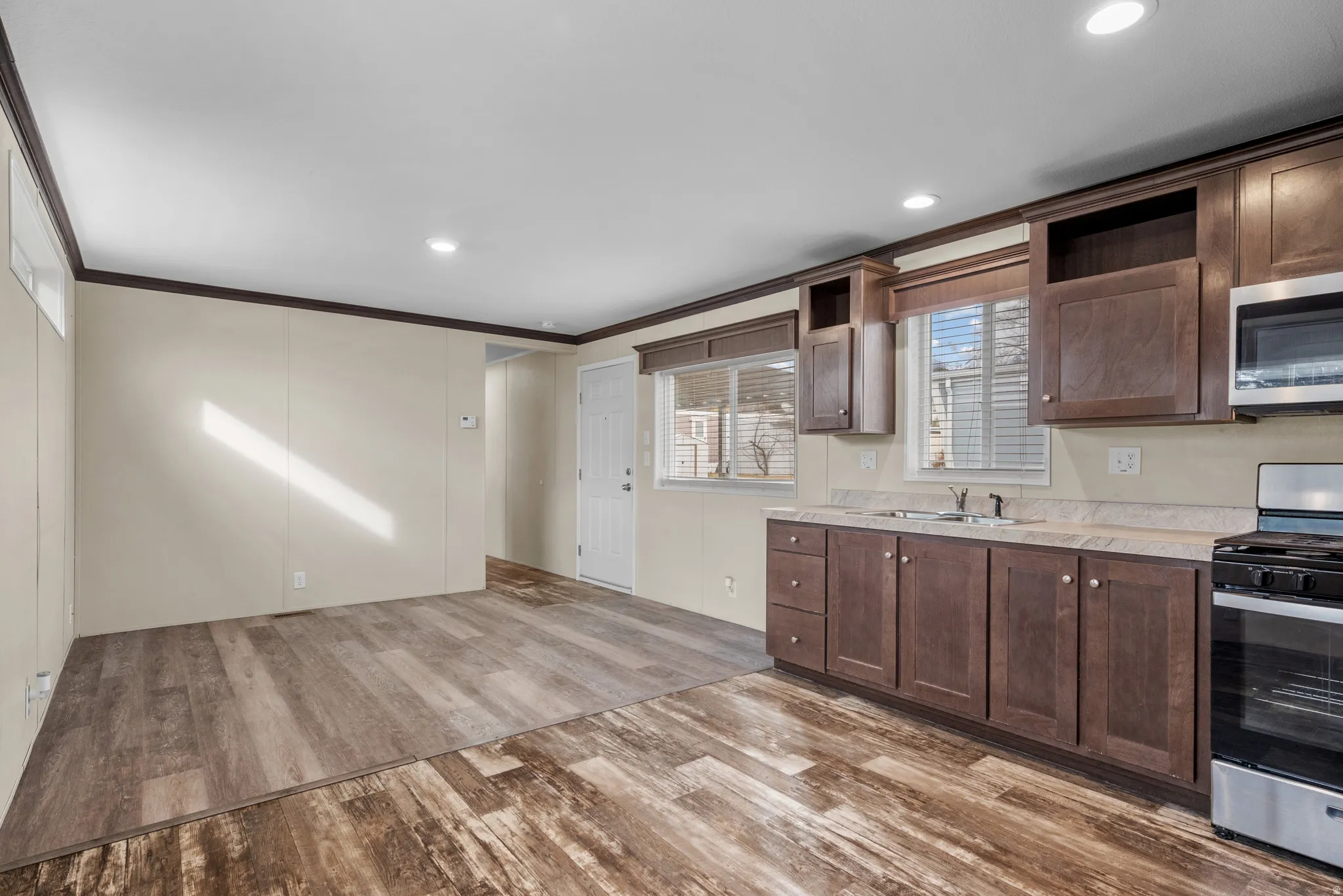 Open-concept living space featuring wood-finish flooring, recessed lighting, and a full kitchen