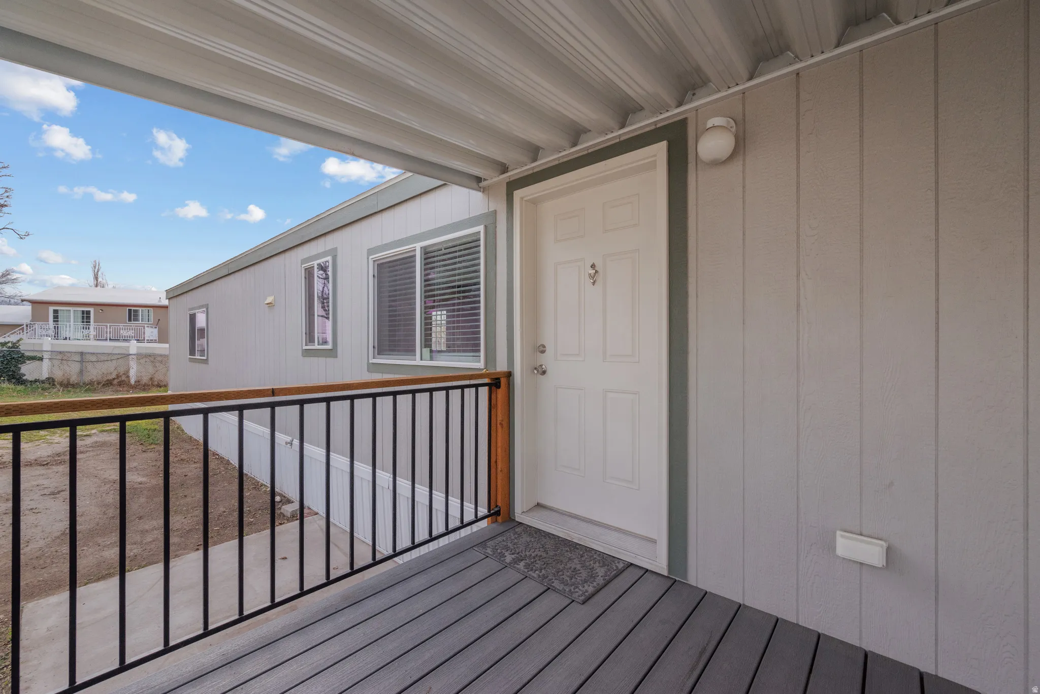 Covered porch entry featuring wood-finish decking and black metal railing