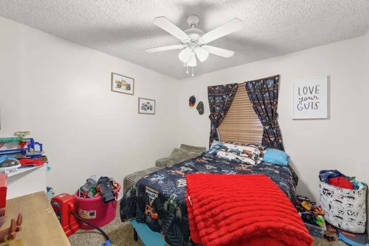 Neutral-toned interior room featuring a ceiling fan, wall-to-wall carpeting, and a window with blinds