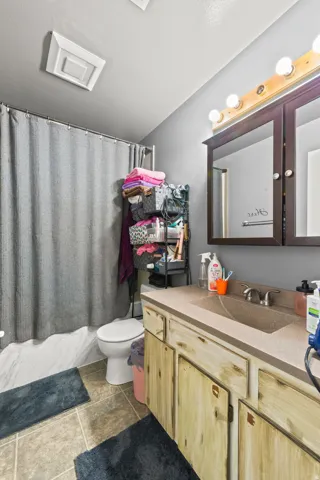 Bathroom featuring a wood-finish vanity with an integrated sink and a vanity mirror with overhead lighting