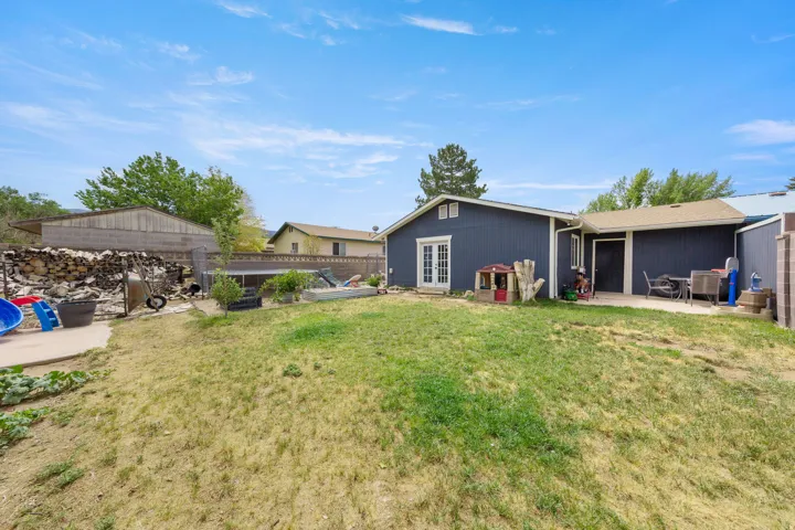 Expansive backyard featuring a central lawn area, a concrete patio, and a second concrete pad