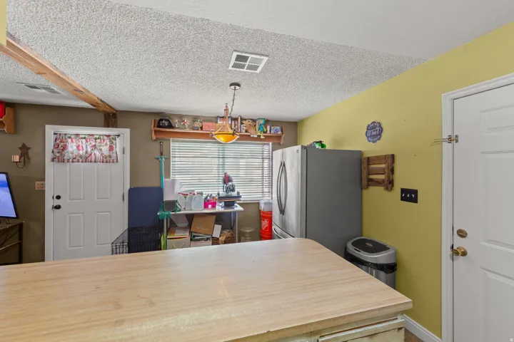 Kitchen area featuring a light-toned countertop island, textured ceiling, and a window with horizontal blinds