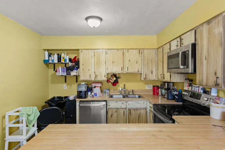 Kitchen featuring wood-finish cabinetry, a stainless steel microwave, a dual basin sink, and a black electric range