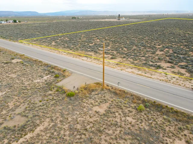 Expansive undeveloped land featuring a paved road frontage and natural desert vegetation