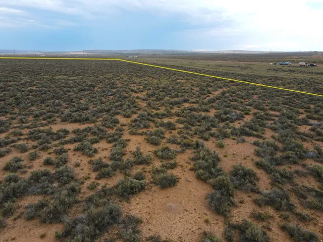 Expansive undeveloped lot featuring a natural, arid landscape with scattered low-lying scrub vegetation and clear boundary lines