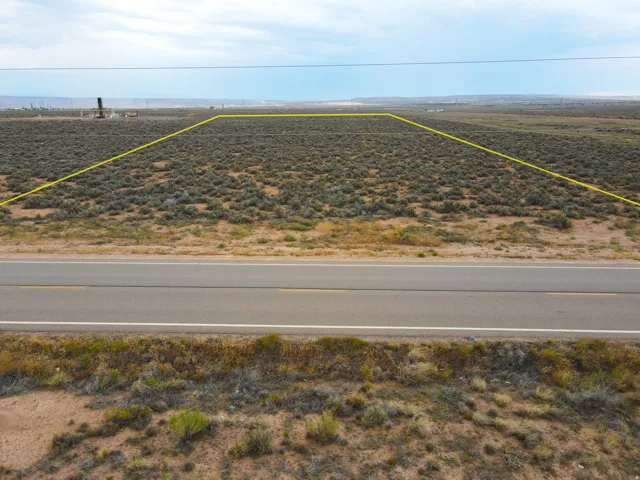 Expansive desert landscape featuring natural brush and a paved road frontage