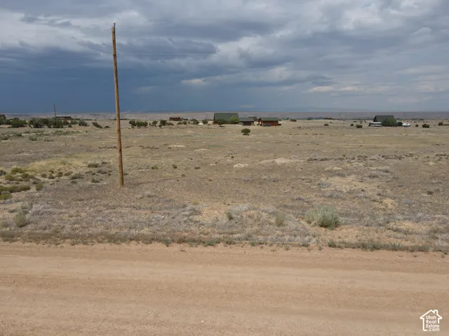 Expansive land parcel featuring natural desert vegetation, a visible dirt road, and utility poles