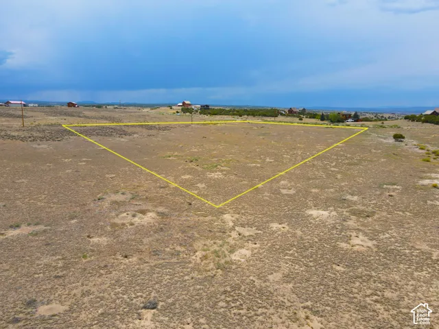 Expansive undeveloped lot with natural ground cover, offering a prominent building area delineated by a yellow boundary