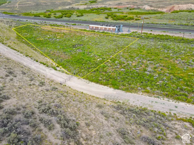 Expansive land parcel featuring natural ground cover, a gravel access road, and proximity to railroad tracks