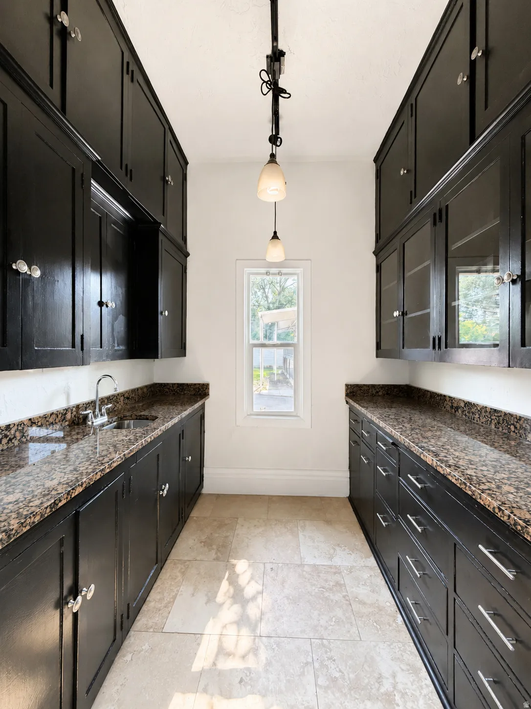 Butler Pantry/Wet Bar. featuring extensive dark cabinetry with varied hardware, granite countertops, and tile flooring